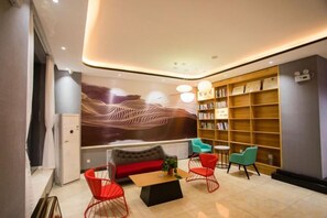 A modern interior with a sofa, red chairs, a coffee table, and a bookshelf. - Shankee Hotel (Xin'an Hangzhou Road) (Xin'an)