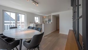 A modern kitchen with a dining area, large windows, and a view of the city. - Apartment in Knokke Near Lippenslaan (Knokke-Heist)