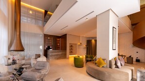 A spacious living area with modern furniture, a fireplace, and a staircase leading to an upper level. - SUITES BY LE REVE  (Tangier)