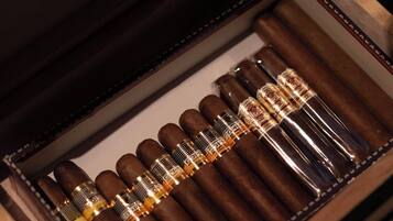 A wooden cigar box with a velvet interior, containing several cigars and a cigar cutter.