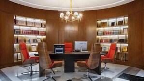 A conference room with a black table, four chairs, a computer, and bookshelves with books and awards. - Zhengzhou Aimu International Hotel (Zhengzhou)