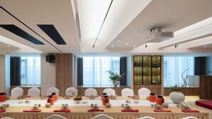 A modern dining area with a long table set for a meal, surrounded by white chairs. - Zhengzhou Aimu International Hotel (Zhengzhou)