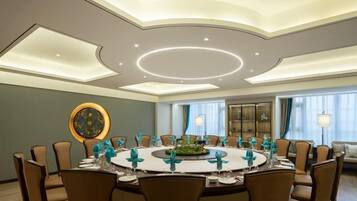 Une salle de conférence équipée d’une table ronde, de chaises et d’un arrangement floral central.