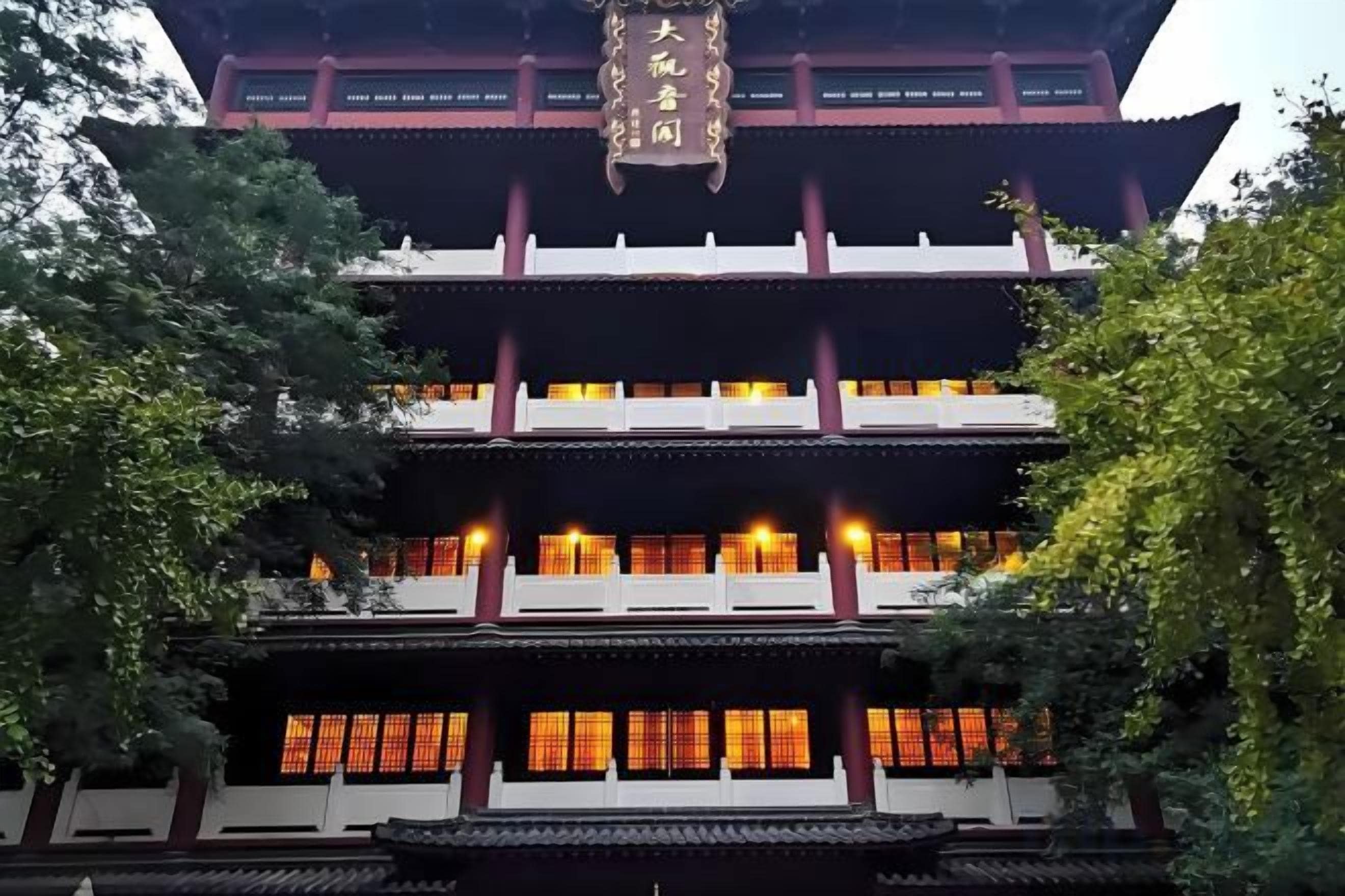 A traditional multi-story building with a prominent entrance and illuminated windows.