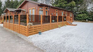 Una baita di legno con veranda, un portico coperto e un vialetto sterrato.
