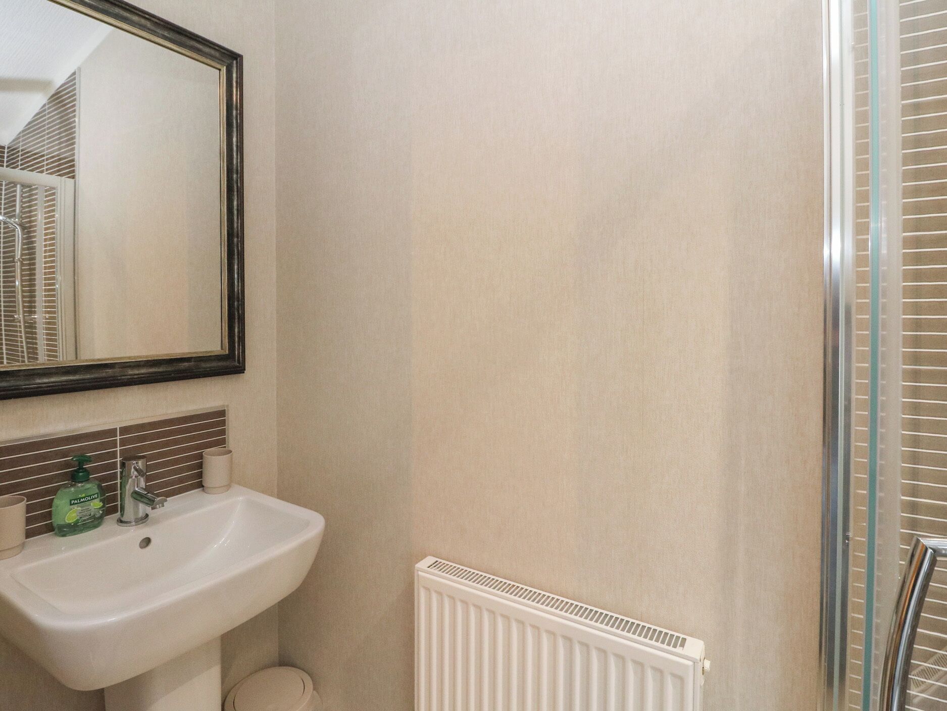 A bathroom with a white sink, a mirror, and a radiator.