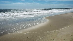 Una playa con una costa curva y cielo despejado.