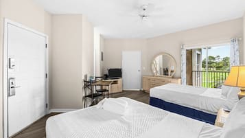Une chambre d’hôtel avec deux lits, un bureau avec un ordinateur, un ventilateur de plafond et un balcon avec vue.