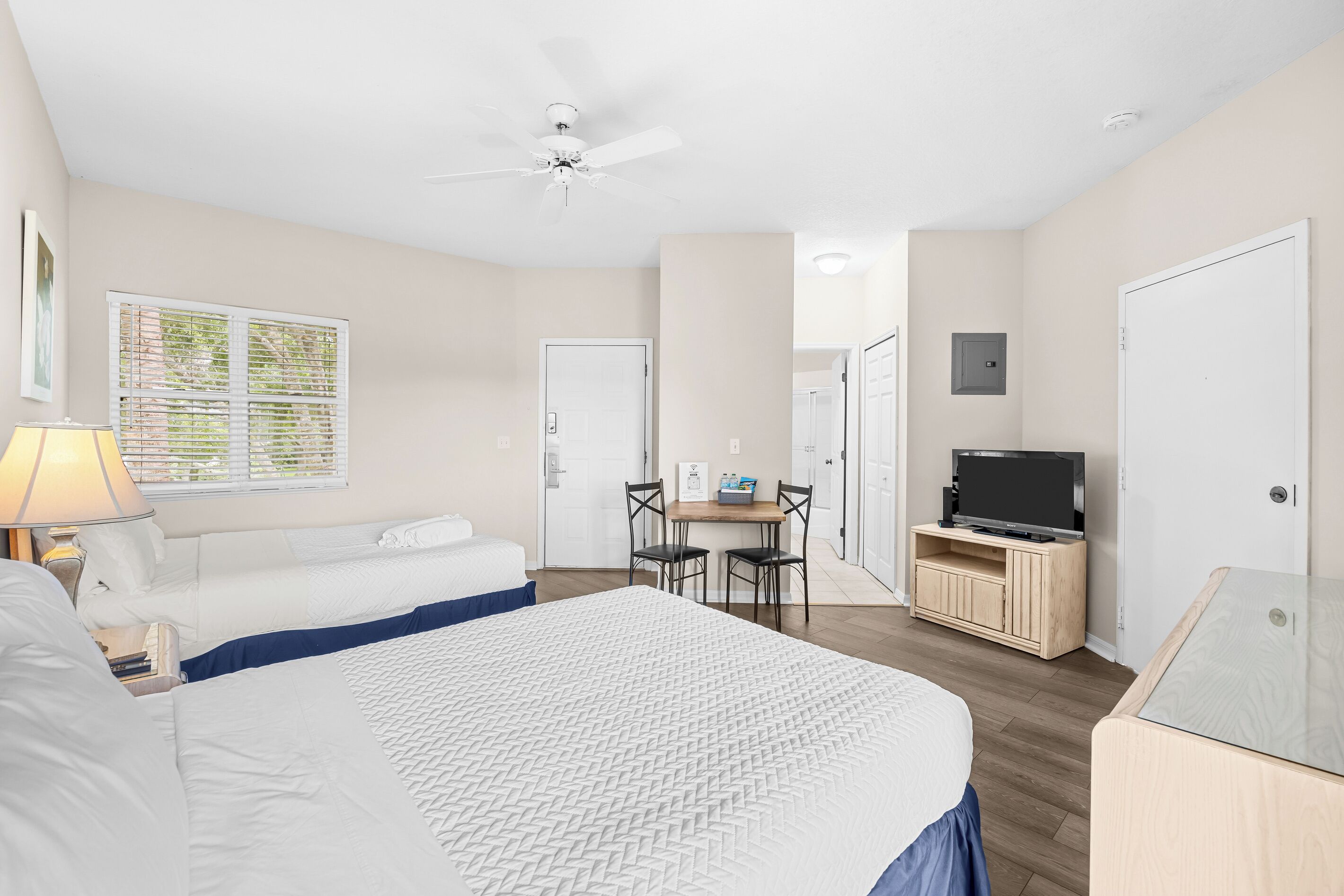 Une chambre d’hôtel équipée d’un lit, d’un bureau avec une chaise, d’une télévision et d’un ventilateur de plafond.