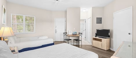 Une chambre d’hôtel équipée d’un lit, d’un bureau avec une chaise, d’une télévision et d’un ventilateur de plafond.