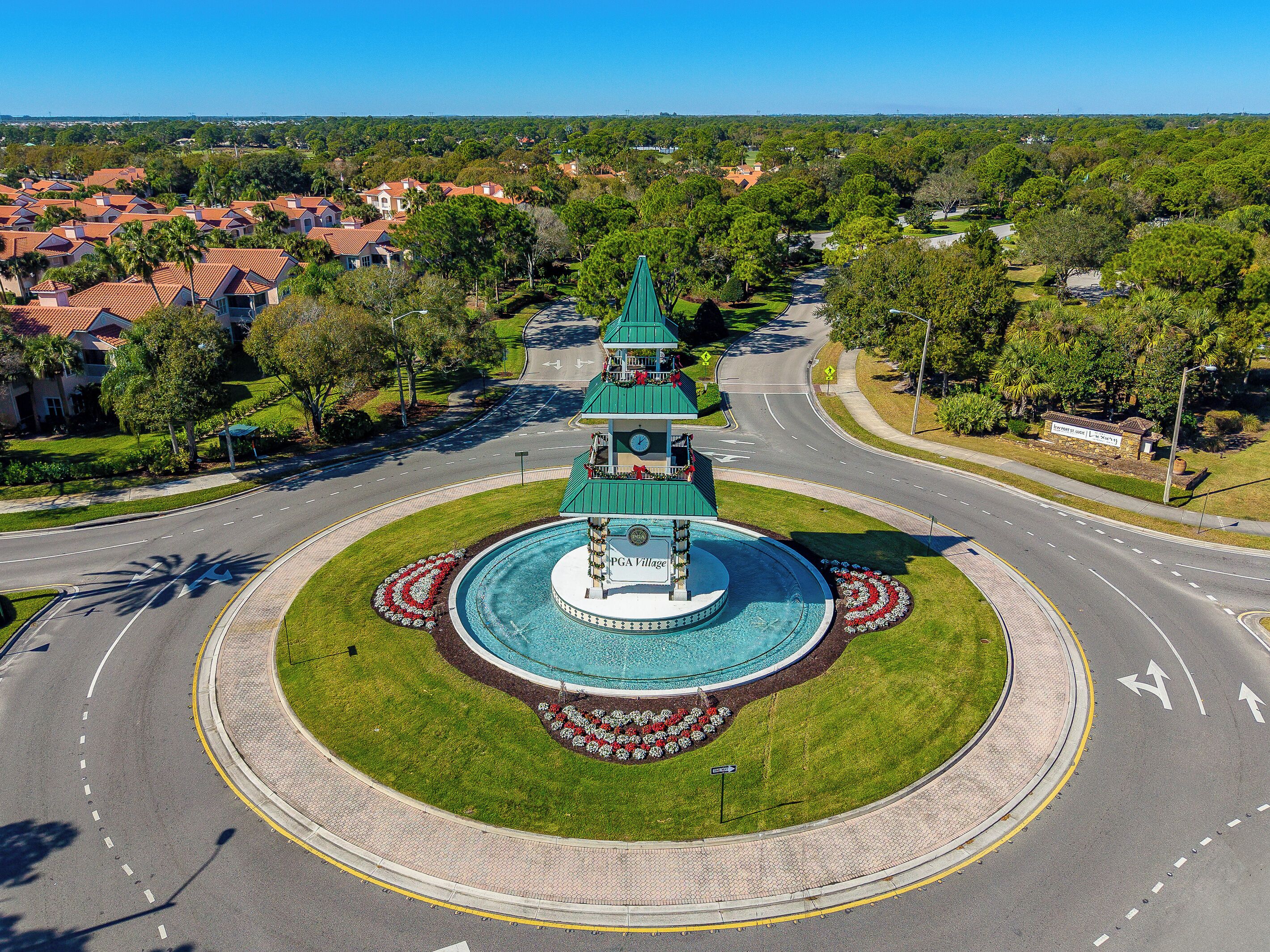 Un carrefour giratoire avec une fontaine centrale, entouré de verdure et sous un ciel dégagé.