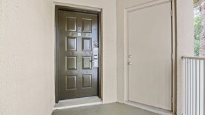 Uma porta com fechadura eletrônica, outra porta simples ao lado e um piso de concreto.