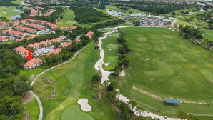 Vista aérea de um campo de golfe com área residencial, um corpo de água e um local demarcado.