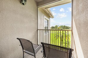 A balcony with two chairs and a view of a green landscape.