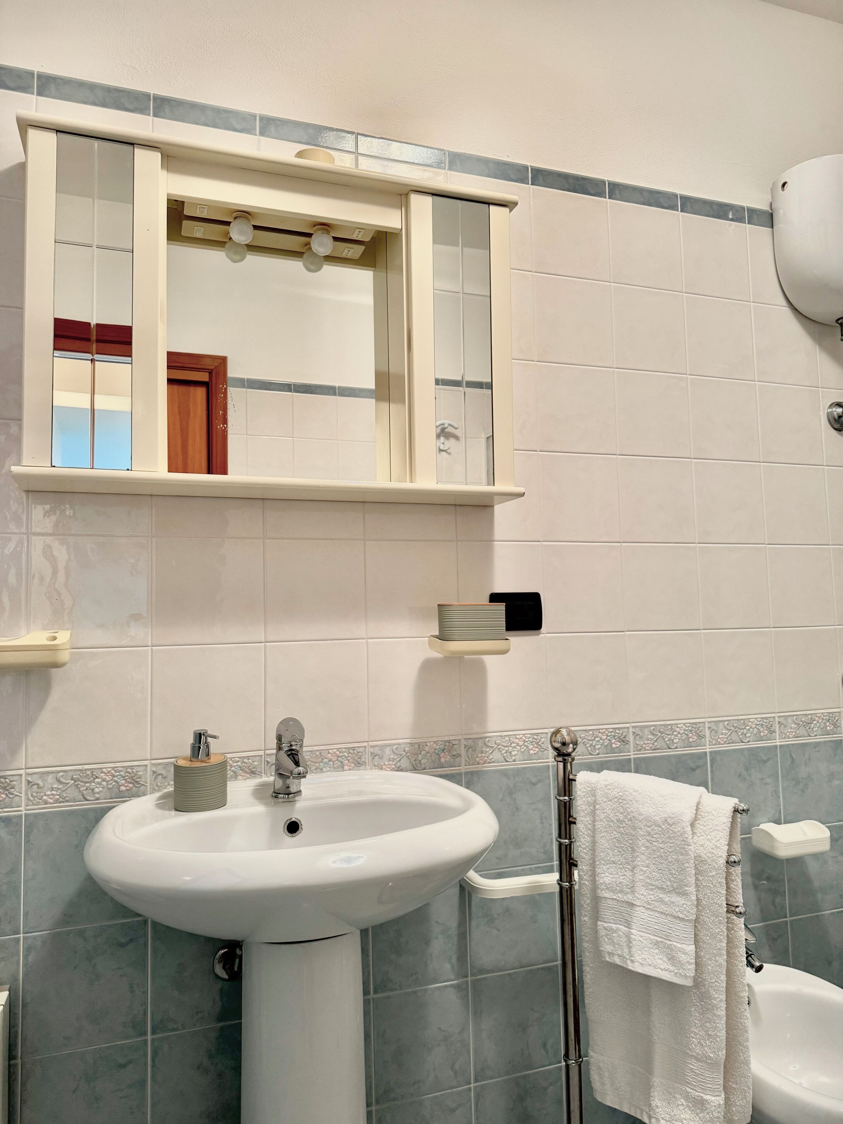 A bathroom with a white sink, a mirror, a towel rack, and a toilet.