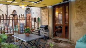 Eine Terrasse mit Tisch, Grill und Gartenmöbeln.