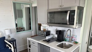 A compact kitchen with a microwave, toaster, coffee maker, and sink.