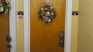A wooden door with a wreath, numbers 506 and 505 on the walls, and a doormat.