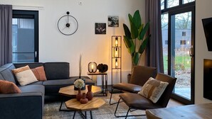 Een moderne woonkamer met een hoekbank, een salontafel en een groot raam met uitzicht op de omgeving.