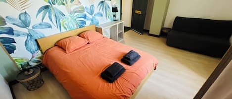 A room with a bed, a sofa, a desk, and a door.