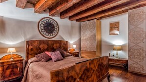 A wooden bed with a headboard, two bedside tables, and a wall with patterned wallpaper. - SUITE HAVEN IN VENICE WITH PRIVATE SPA (Venezia)