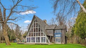 Une grande maison en bois, dotée d’un toit triangulaire imposant et de nombreuses fenêtres.