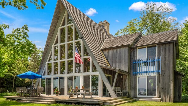 Une cabane en bois avec une grande fenêtre, un drapeau et une table de pique-nique.