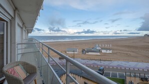 A balcony with a view of a beach, a chair, and a small table. - Studio in Duinbergen With Sea Views (Knokke-Heist)
