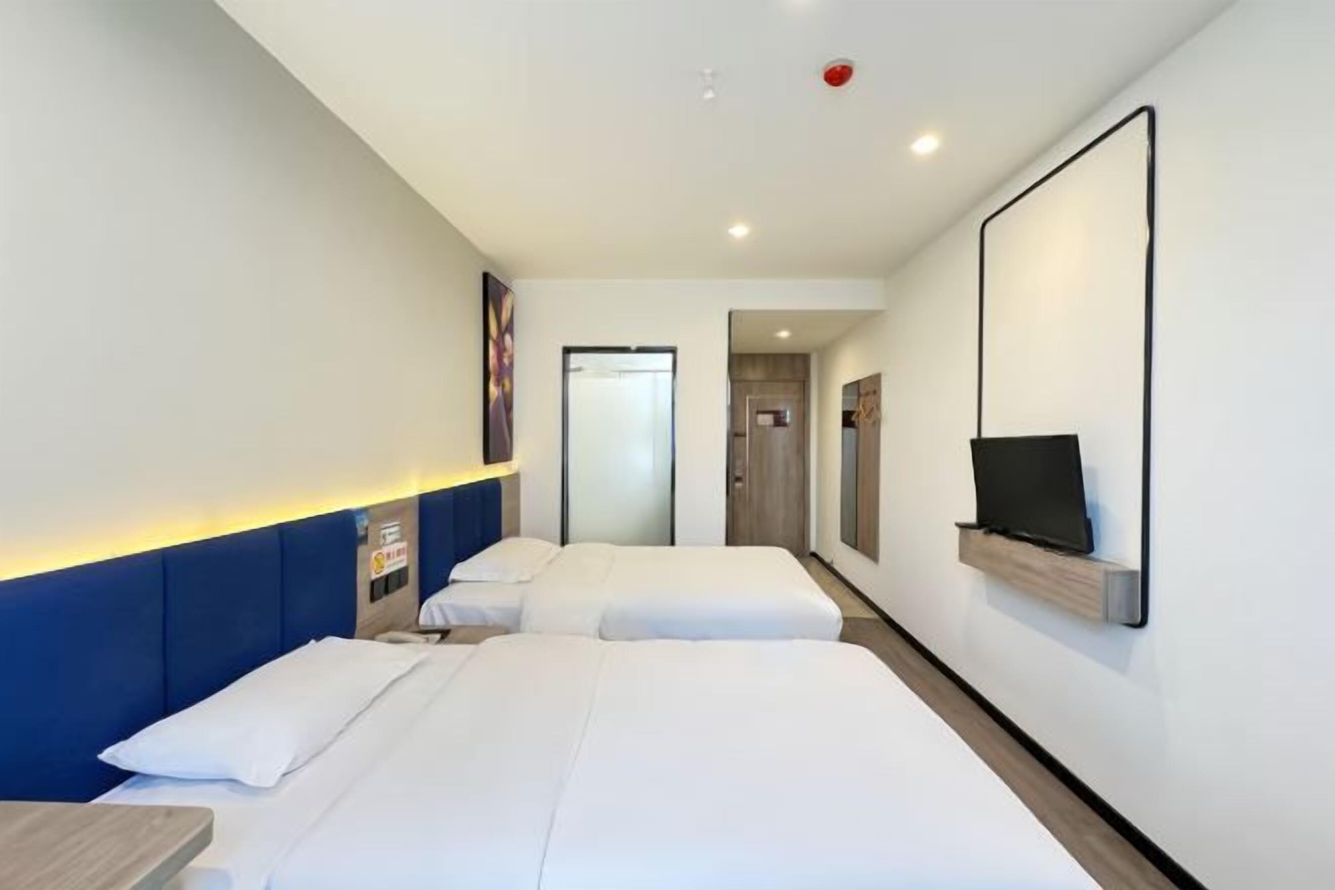 Quarto de hotel com duas camas, televisão na parede e uma pequena mesa.