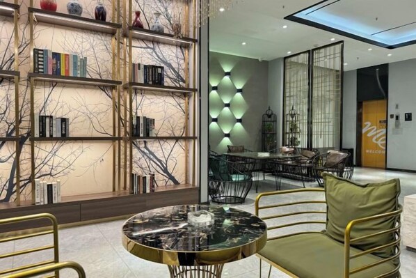 A modern interior with a round table, chairs, a bookshelf, and a dining area. - Elong ME Hotel (Shijiazhuang Railway Station Xinshizhong Road) (Shijiazhuang)