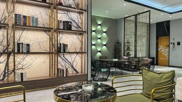 A modern interior with a round table, green upholstered chairs, and a bookshelf with books. - Elong ME Hotel (Shijiazhuang Railway Station Xinshizhong Road) (Shijiazhuang)