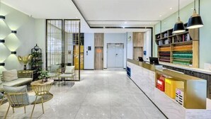 A modern hotel lobby with a reception desk, seating area, and a large window. - Elong ME Hotel (Shijiazhuang Railway Station Xinshizhong Road) (Shijiazhuang)