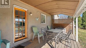 Eine überdachte Terrasse mit Tisch und Stühlen, ein Holzdeck und eine Schmetterlingsdekoration an der Wand.