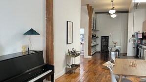 Un vaste salon agrémenté d’un magnifique piano à queue, d’un parquet en bois et d’un coin repas avec des chaises au design moderne.