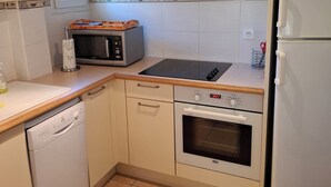 Cocina compacta con lavavajillas, microondas, estufa, horno y refrigerador.