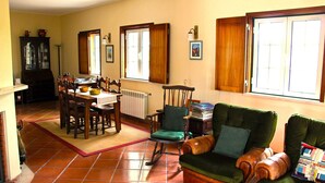 Un comedor con una mesa y sillas de madera, una mecedora y un sillón verde.