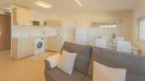 A compact living space with a kitchenette, a sofa, a dining area, and a washing machine. - Vistas increíbles en Laredo (Laredo)