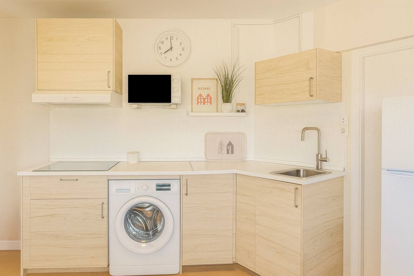 A compact kitchen with a washing machine, a sink, and a clock on the wall.