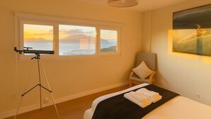 A bedroom with a bed, a chair, a tripod, and a painting.