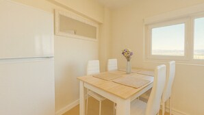 A dining area with a table, chairs, a vase with flowers, and a window with a view.