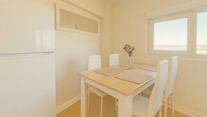 A dining area with a table set for four, white chairs, a vase with flowers, and a window with a view. - Vistas increíbles en Laredo (Laredo)