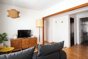 A living room with a sofa, a television on a wooden cabinet, a lamp, and a plant. - Casa Camilo - Retro con Encanto (Santander)