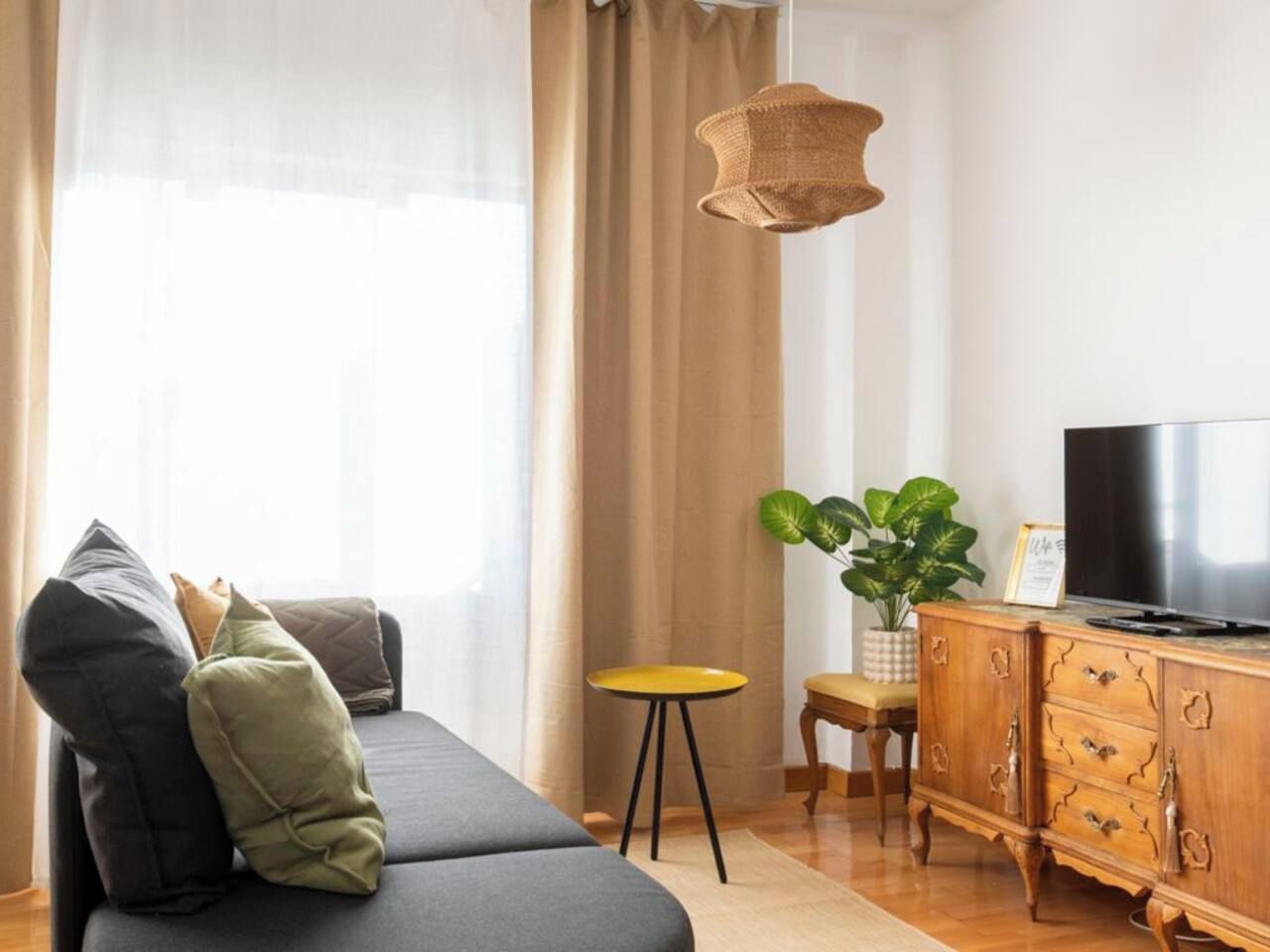 Moderni olohuone, jossa on sohva, televisio, puinen kaappi ja pieni pöytä.