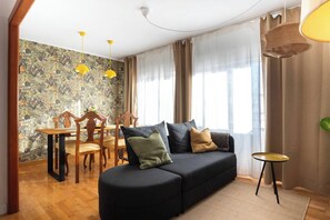 A living room with a sofa, a dining table with chairs, and a small side table.