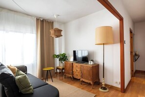 A living room with a sofa, television, wooden cabinet, and a lamp. - Casa Camilo - Retro con Encanto (Santander)