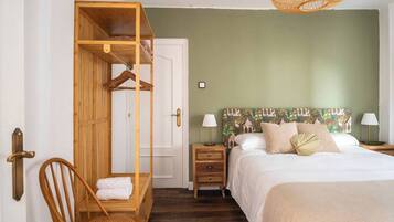 A bedroom with a bunk bed, a single bed with a patterned headboard, bedside lamps, and a wicker hanging chair.