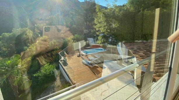 A balcony with a view of a swimming pool, lush greenery, and a mountainous backdrop. - Amazing villa 10 min to Monaco (Roquebrune-Cap-Martin)