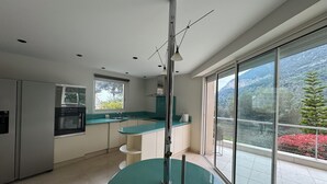 A modern kitchen with a large island, a built-in oven, and a window overlooking a mountainous landscape. - Amazing villa 10 min to Monaco (Roquebrune-Cap-Martin)