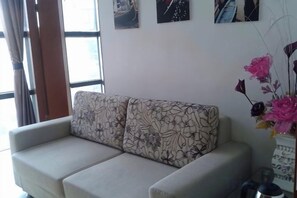Ein Wohnzimmer mit einer Couch, einer Vase mit Blumen und Kunstwerken an der Wand.