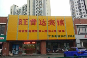 A hotel with a prominent yellow sign, multiple floors, and a visible entrance. - Wangpuda Hostel (Shanghai)